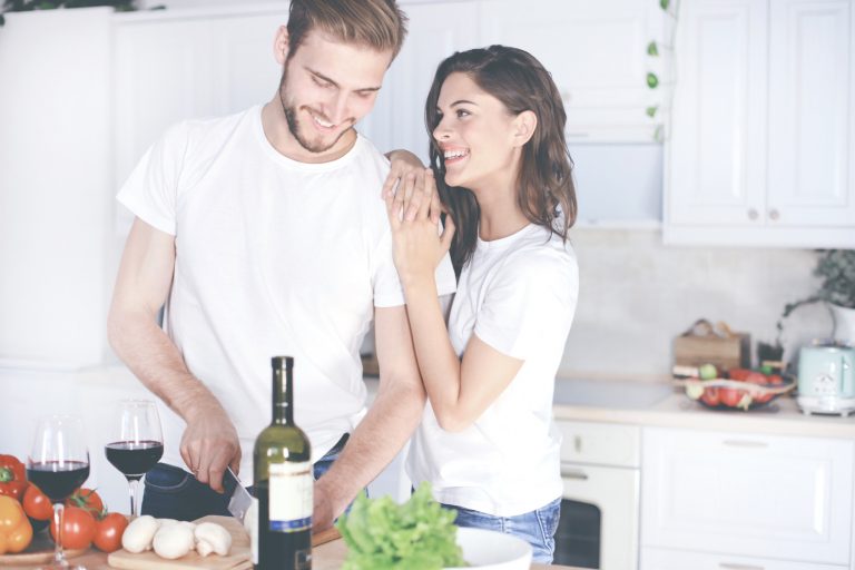 Beautiful young couple preparing a healthy meal together while spending free time at home.